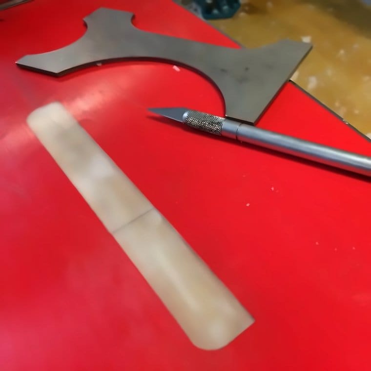 Base patch material and a hobby knife on a red workbench