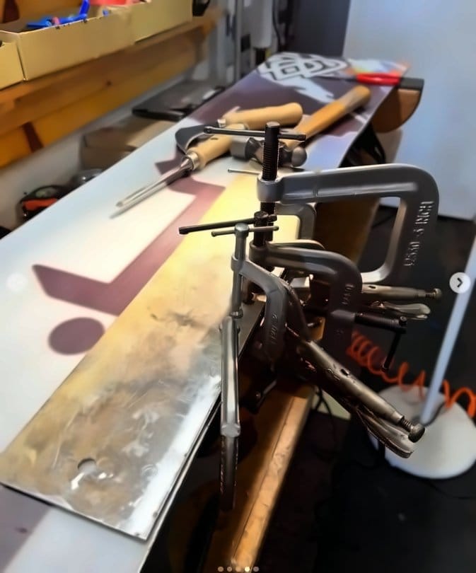 Clamps holding a base patch on a snowboard while it bonds