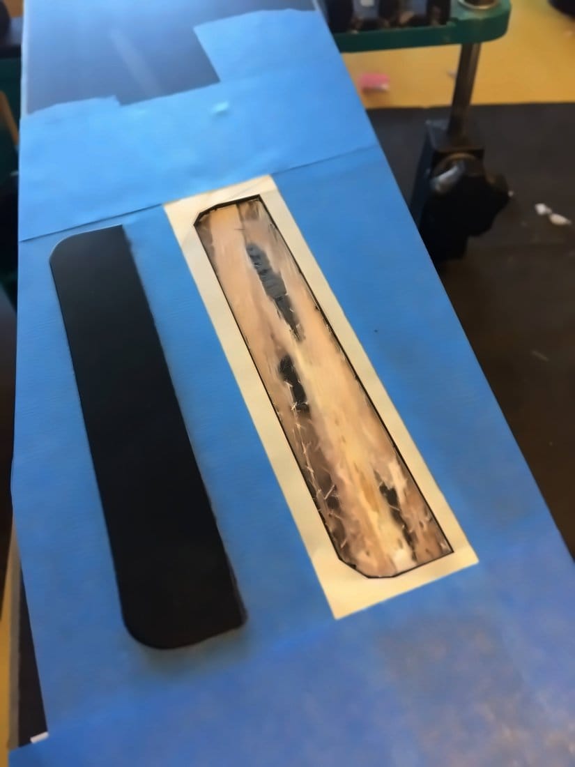 Core shot on a ski base masked off with blue tape before a base patch