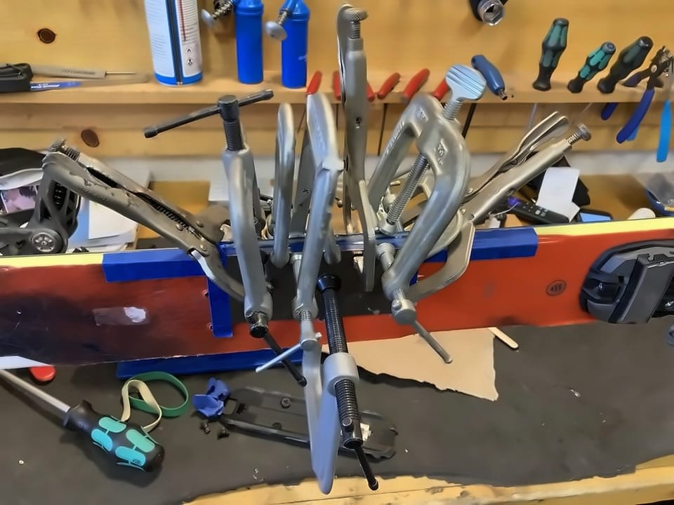 Rows of clamps holding a ski repair at the workbench