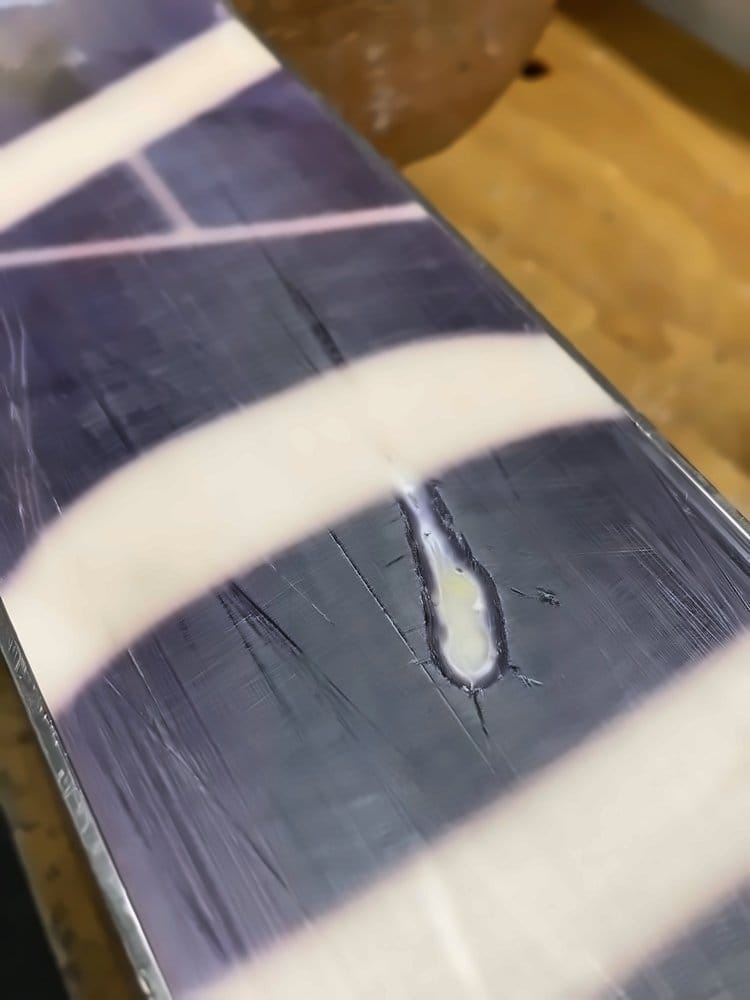 Botched do-it-yourself base repair, with razor blade scratches across the ski base, before Stubborn Goat fixed it with a bonded base repair