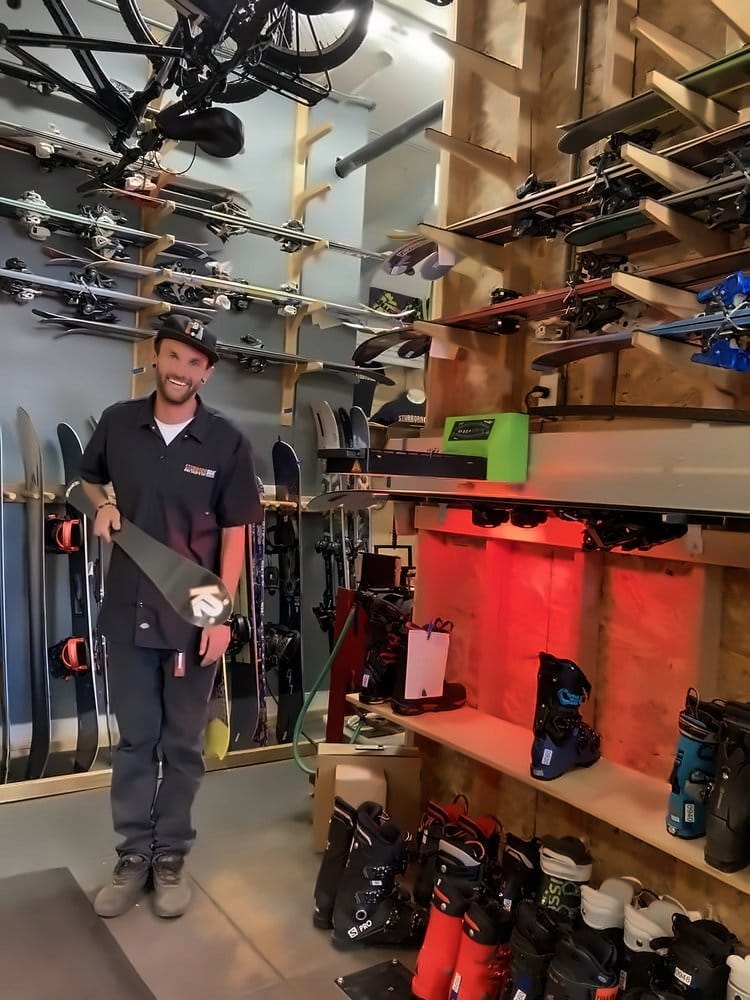 Technician holding a waxed ski, ready to scrape and buff