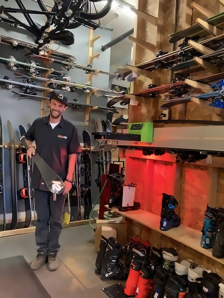Smiling technician holding a finished ski in the shop