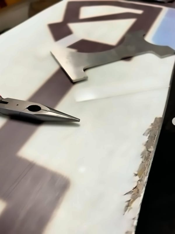 Damaged snowboard base with a patch template laid over it before repair