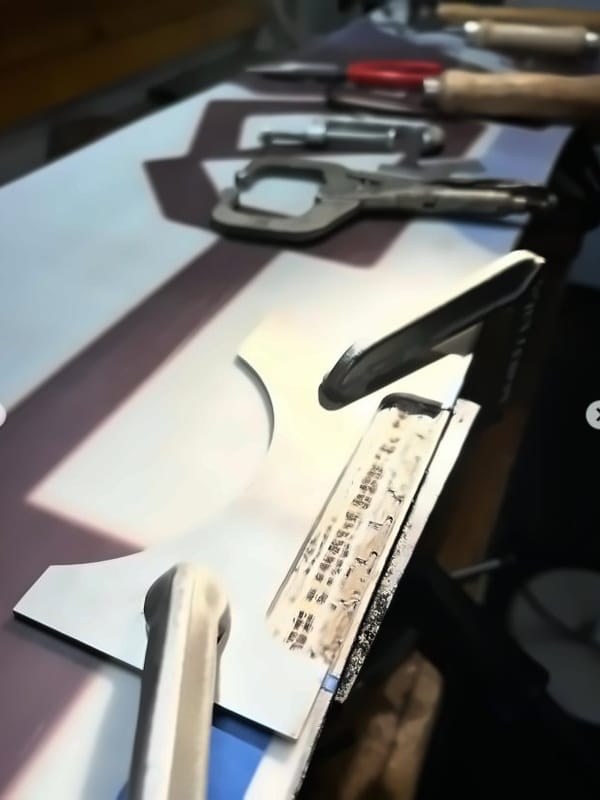 Damaged base material cut away from a snowboard, with clamps and tools on the bench
