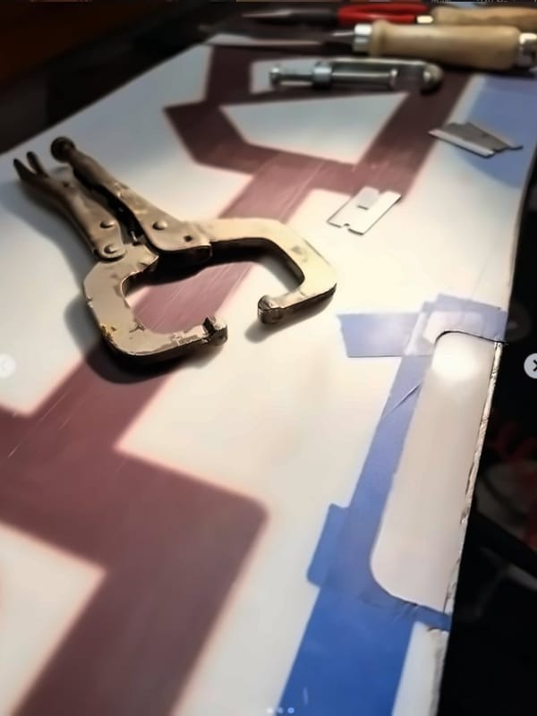 Replacement base patch cut to shape next to the prepared snowboard base