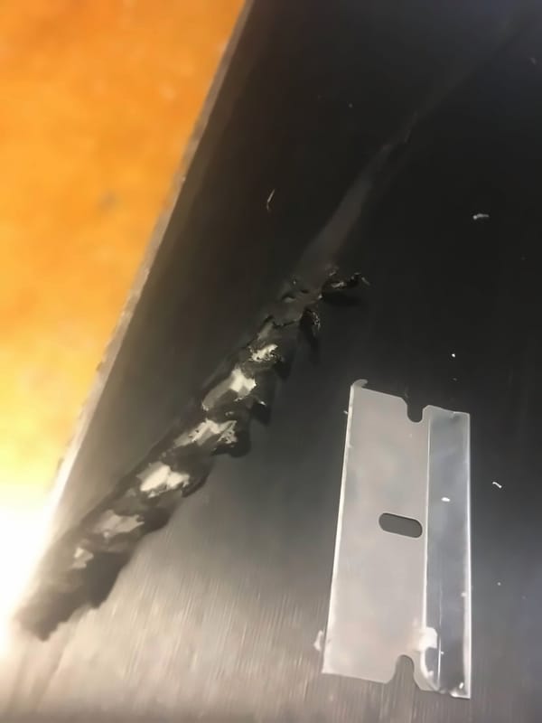 Gouge in a ski base cut out and beveled next to a metal scraper, ready for welding